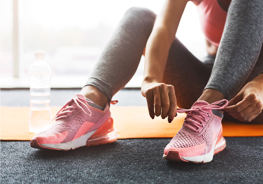 image d'une femme qui fait ses lacets de ses chaussures de sport en intérieur