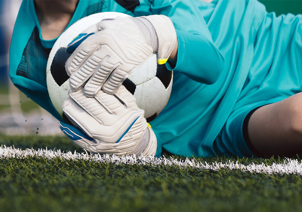 image gardien qui se jette pour récupérer le ballon de football