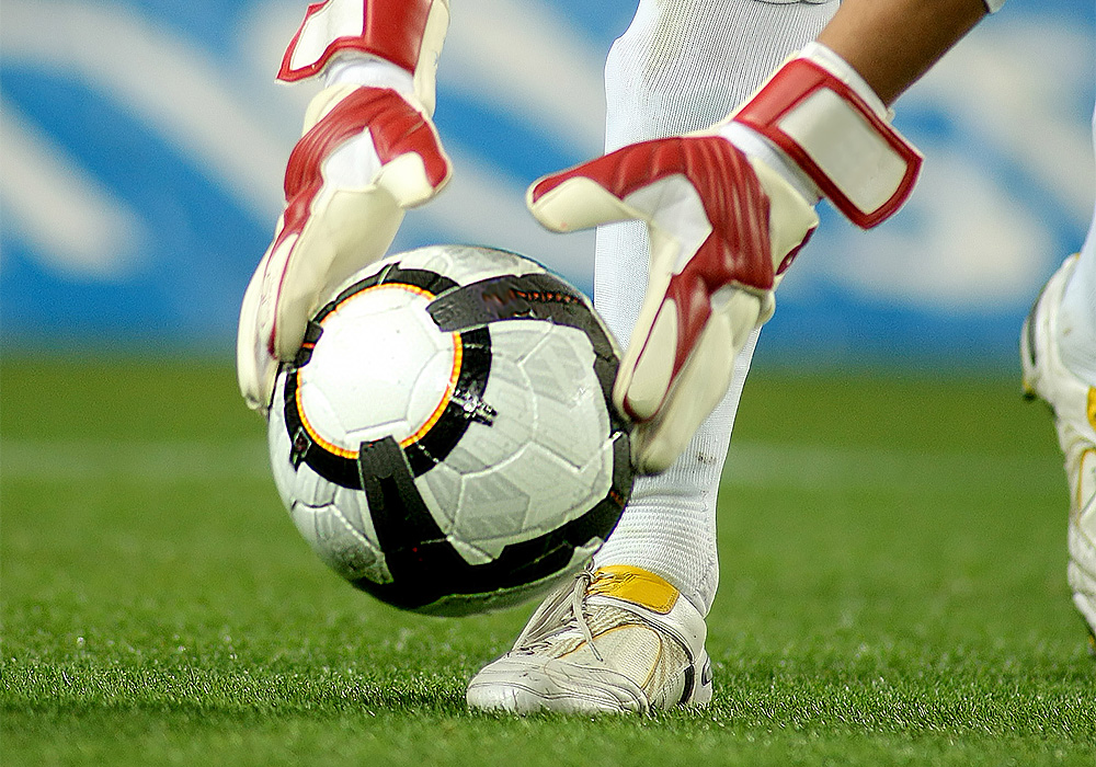 image gardien qui dépose un ballon de foot avec des gants rouges