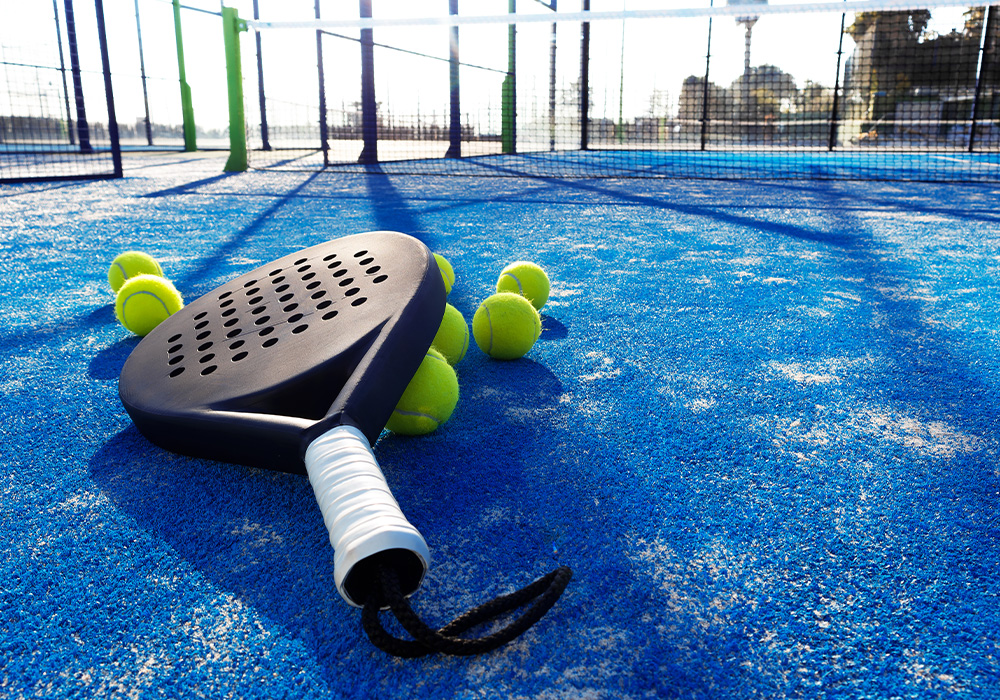 raquette de padel avec des balles sur un terrain de padel bleu