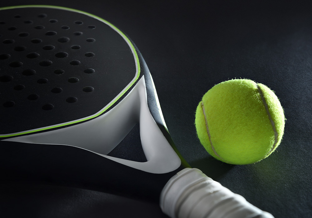 raquette de padel noire sur un fond noir avec une balle