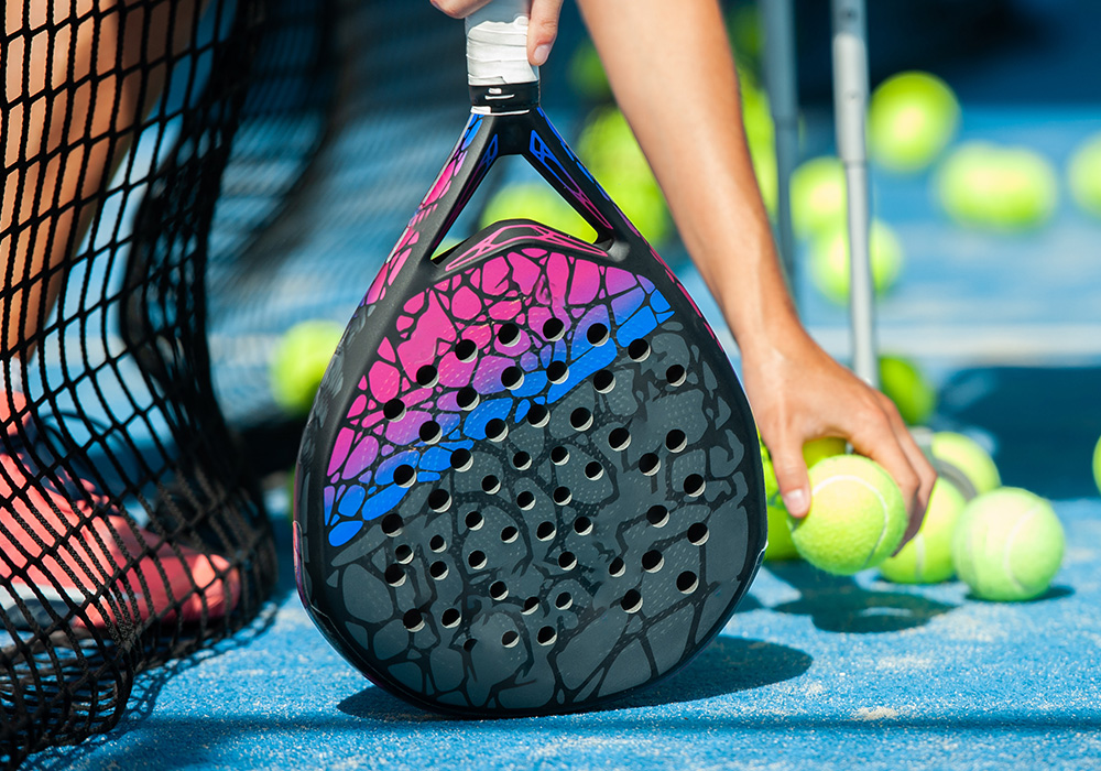 raquette de padel en forme de goutte d'eau en gros plan sur un terrain de padel